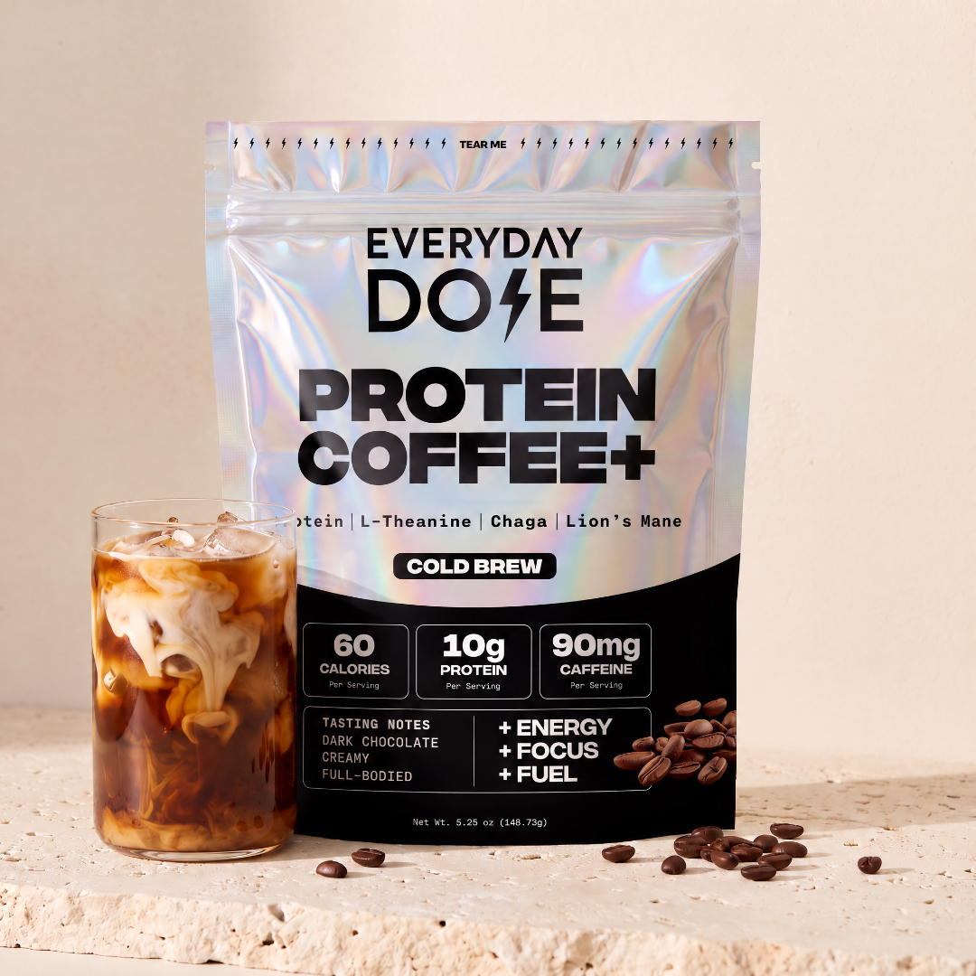 Everyday Dose Protein Coffee+ Cold Brew with iced coffee and scattered beans on travertine