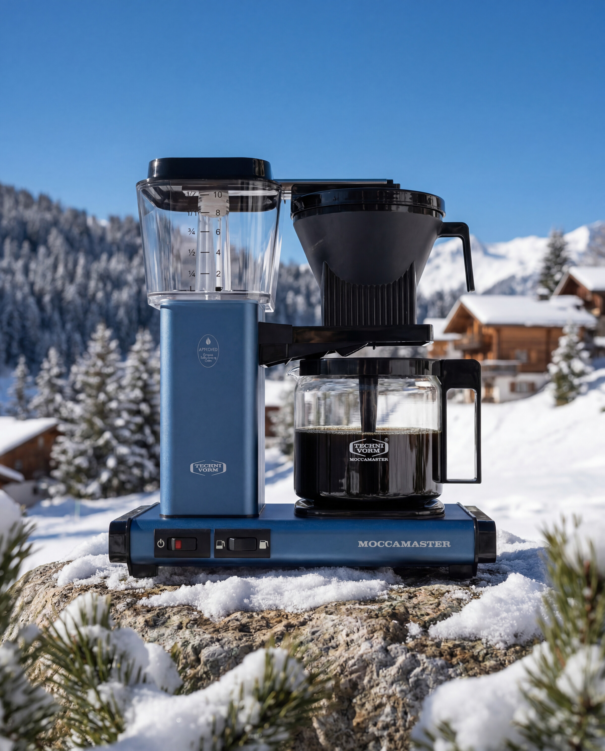 Moccamaster product still - Brewer on stone in front of a mountain village